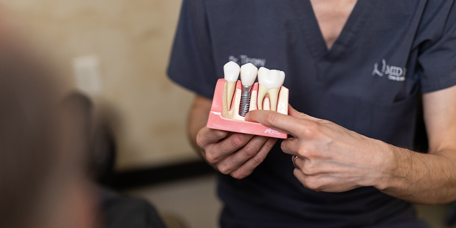 surgical assistant holding a model of dental implants