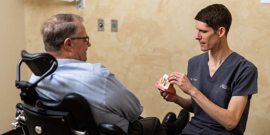 surgeon showing a patient and example of dental implants